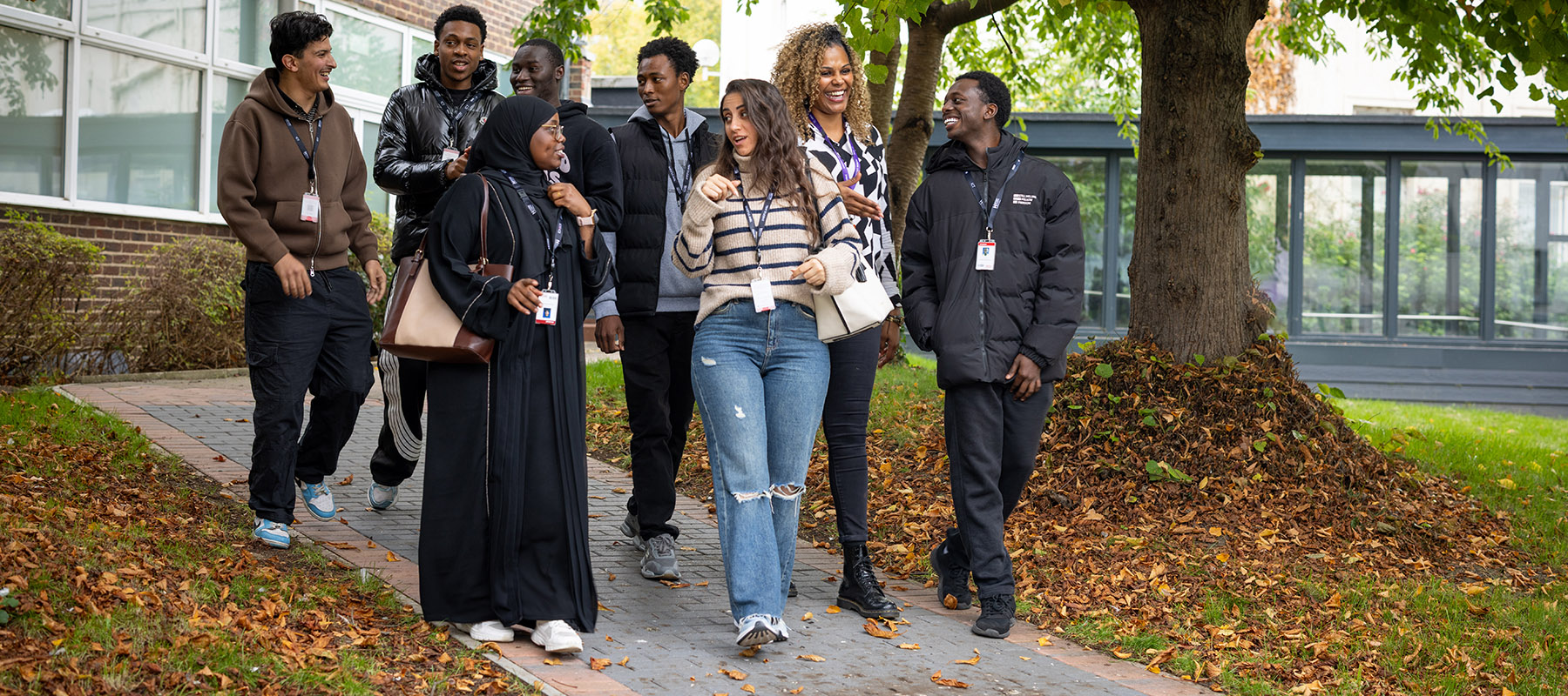A group of students and a staff member from Harrow College talking and walking through the quad in the middle of the Harrow on the Hill campus.  