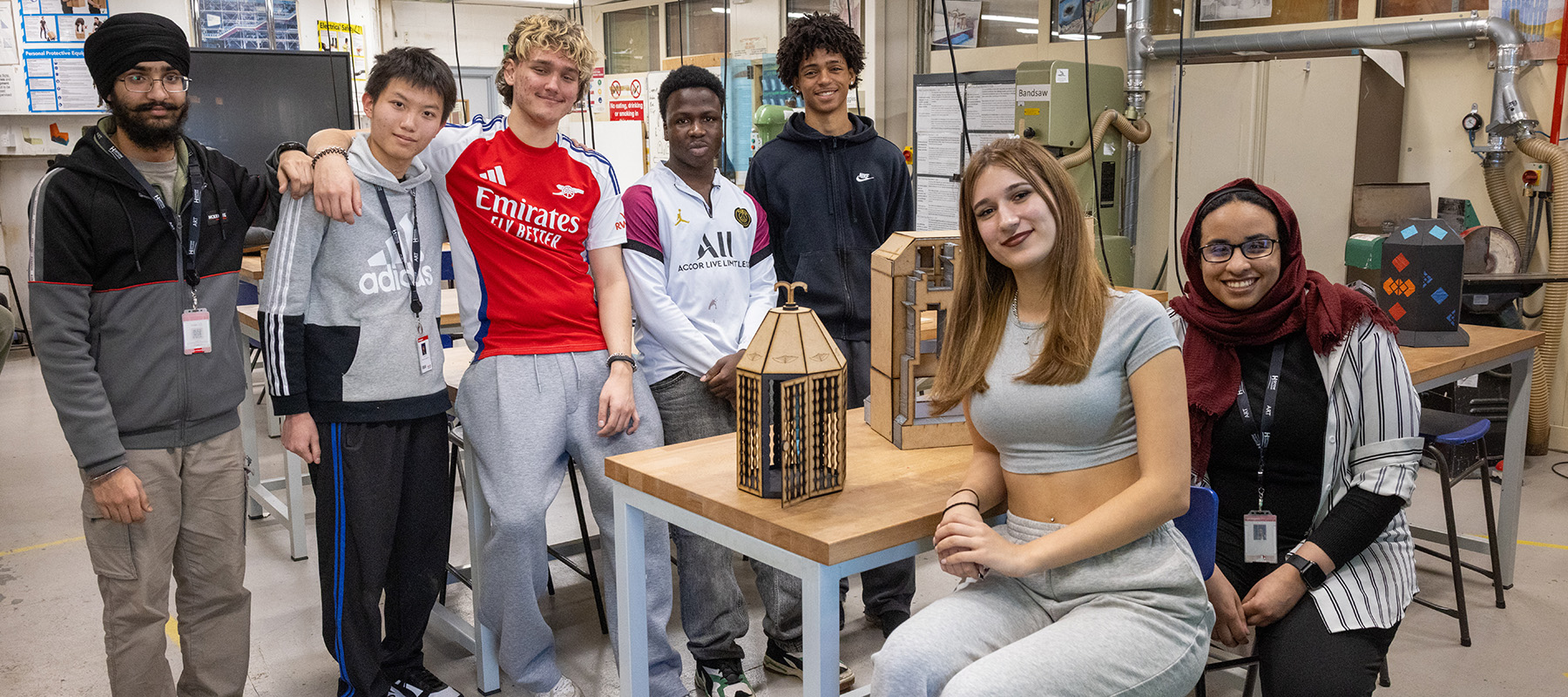 A group of Harrow College students in one of Harrow Weald's workshop spaces with equipment behind them.