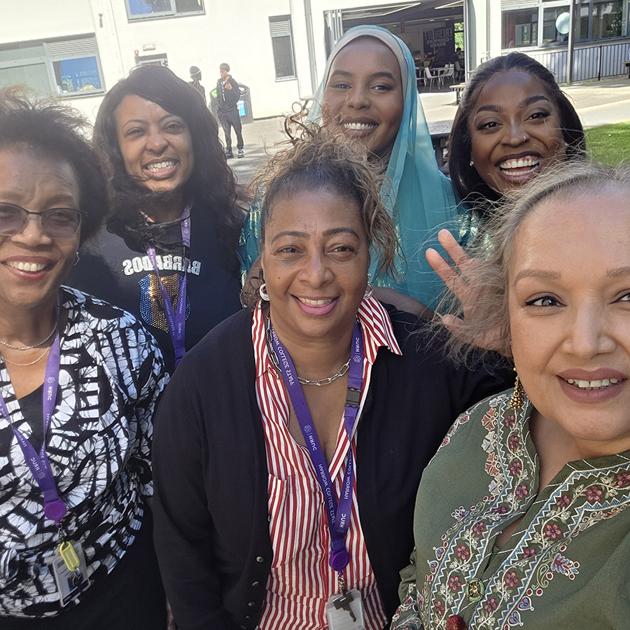 Female Harrow College staff members at the Fusion Fiesta Culture Day. They are outside in the courtyard with a couple wearing the fashion of their cultures.