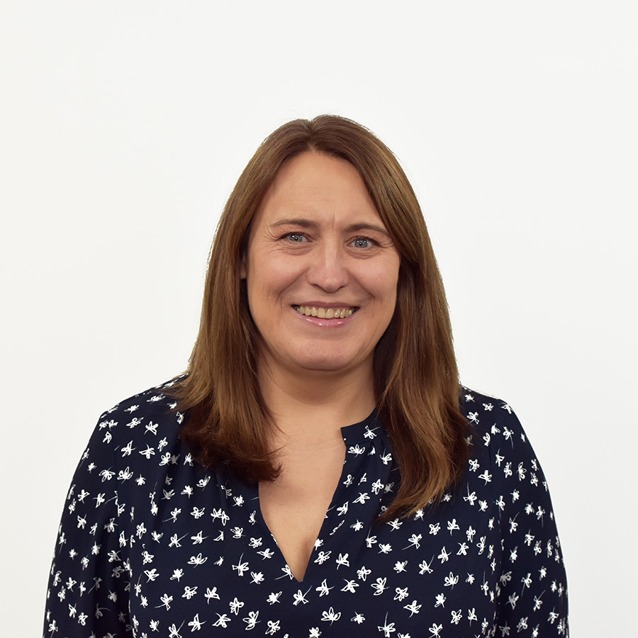 Jo Swindells, new Principal of Harrow College - she is wearing a navy open collar top with white flowers and has shoulder length brown hair.  