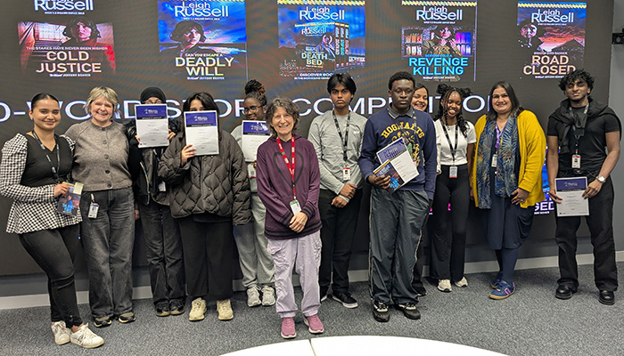Harrow College GCSE English Language Grade 3 students  who took part in the Young Writers Stranger Sagas competition with Leigh Russell, bestselling author. They are standing with their teacher and certificates in hand in the Immersive Room in front of a screen with pictures of Leigh Russell's books.