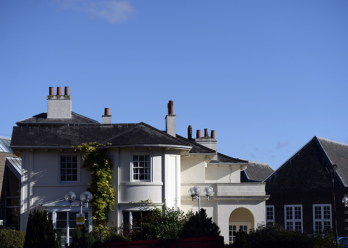 The White House at Harrow on the Hill, Harrow College - Grade II listed building. It has 4 chimneys and there is bright blue sky above the white house. 