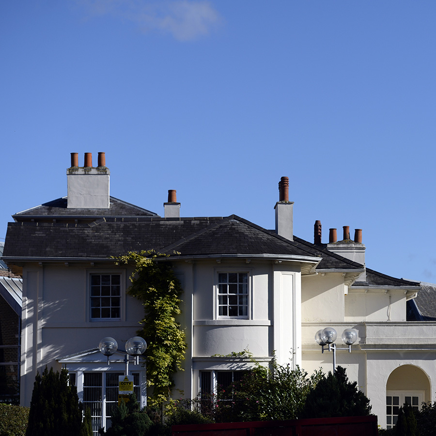 The White House at Harrow on the Hill, Harrow College - Grade II listed building. It has 4 chimneys and there is bright blue sky above the white house. 